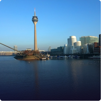 Blick auf den Rheinturm und moderne Gebäude in Düsseldorf am Rhein bei klarem Himmel.