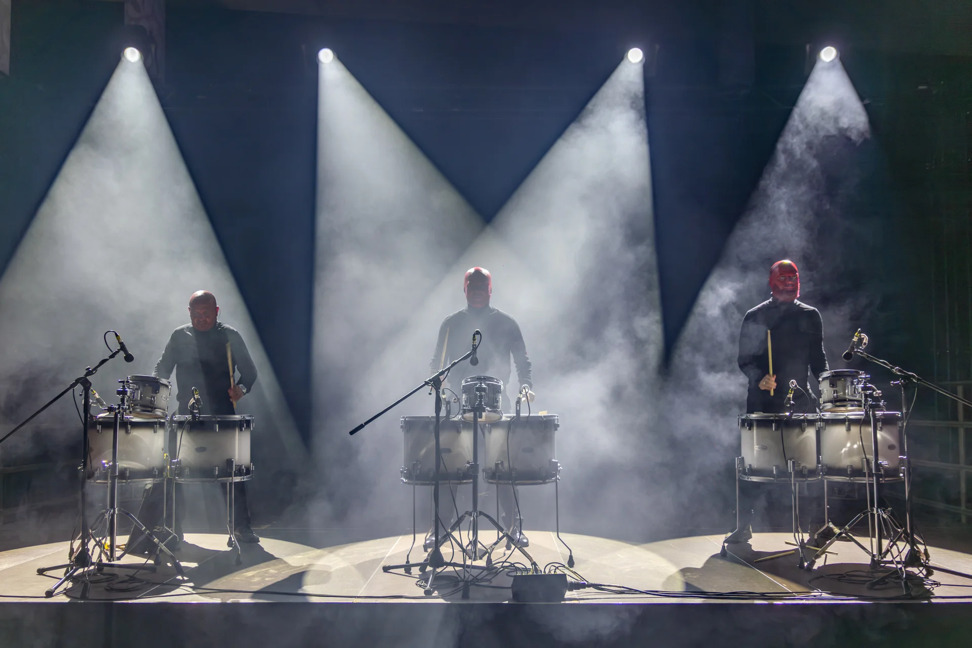 Drei Trommler der Gravity Drumshow stehen auf der Bühne beim GSW-Lichtermarkt Bergkamen, dramatisch beleuchtet durch Spotlights und Nebel.